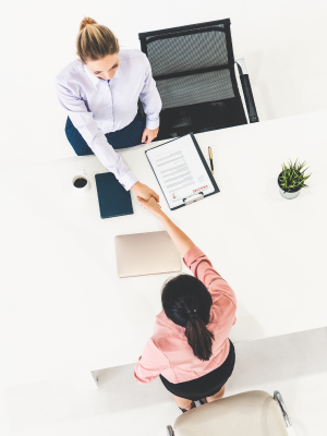 Two professionals shaking hands across a meeting desk